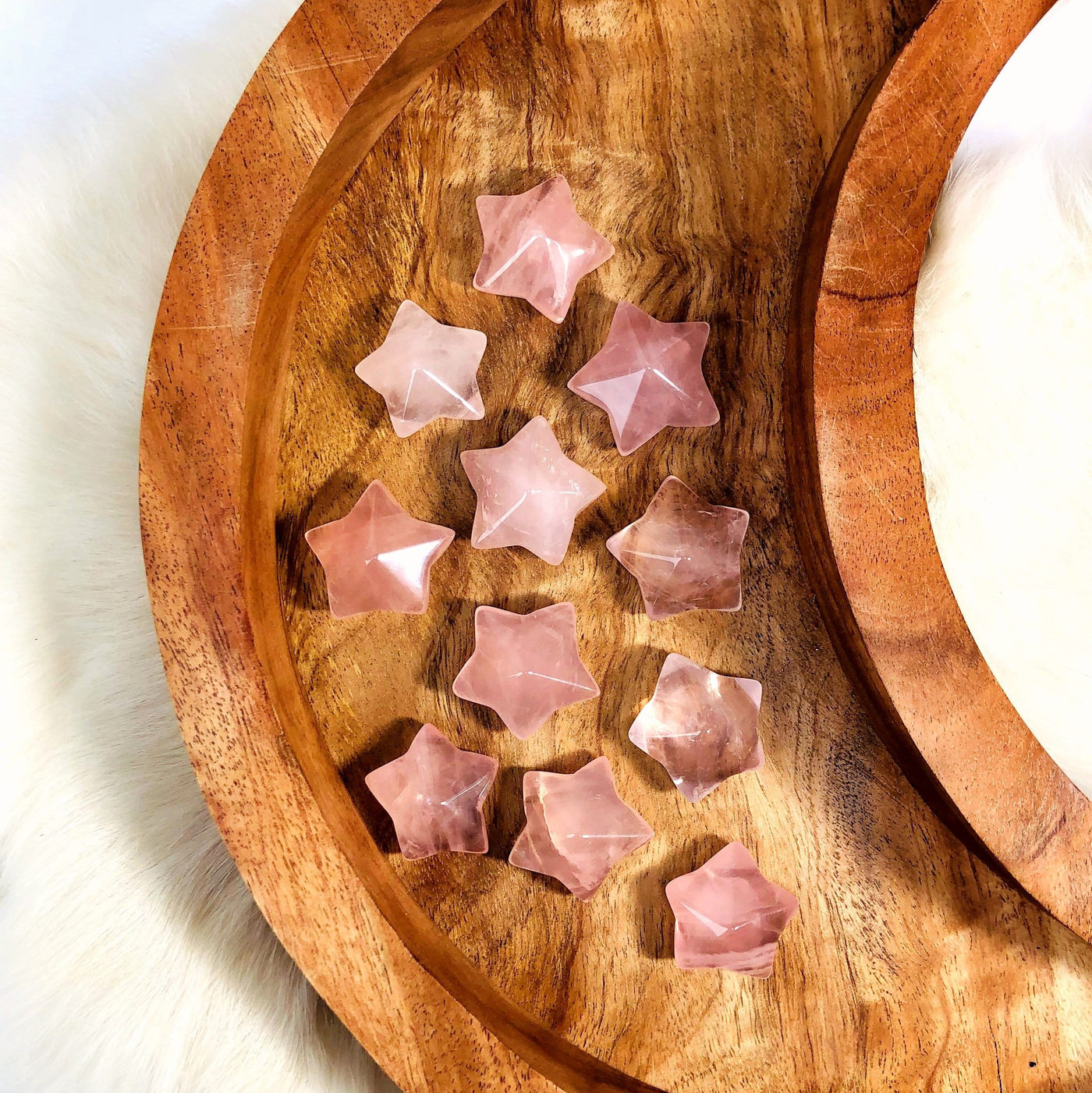 Eleven Rose Quartz Puffy Star Cabochon Gemstones displayed on a wooden moon shaped tray.