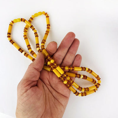 2 Amber Beaded Necklaces with Assorted Beads in a hand for size reference