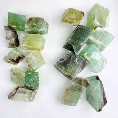 Green Calcite Stones small and large laid out on a white background