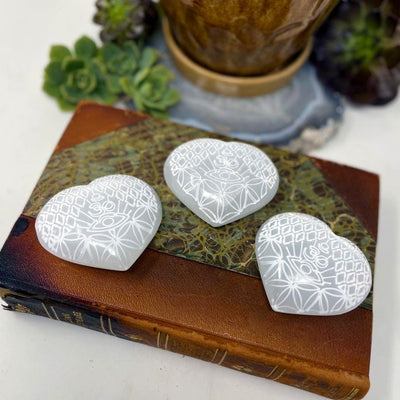 three selenite stone hearts with eye engraving on display