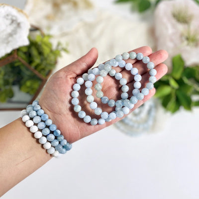 wrist wearing larimar bead bracelets with decorations in the background