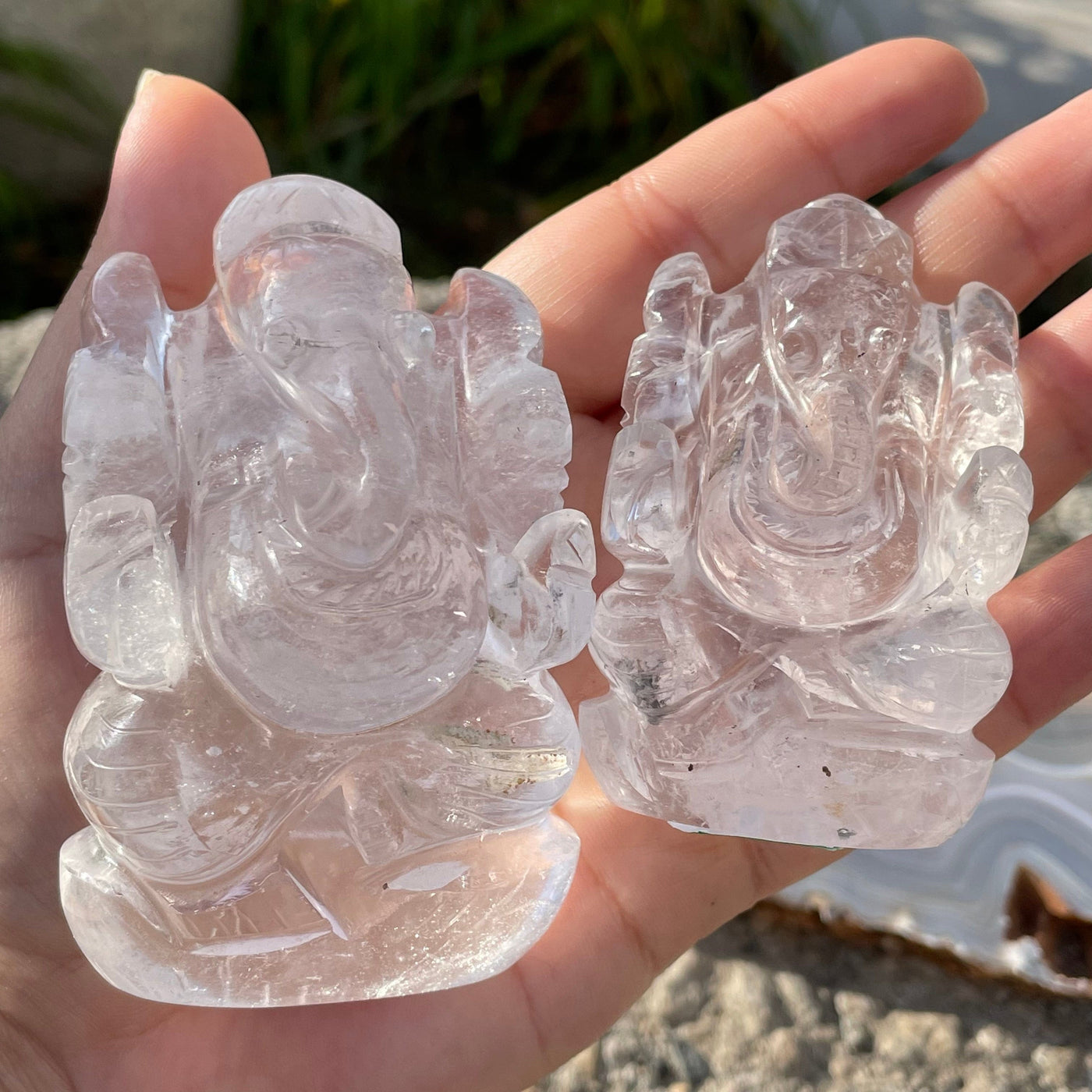 two carved crystal quartz ganesha elephants in hand for size reference 