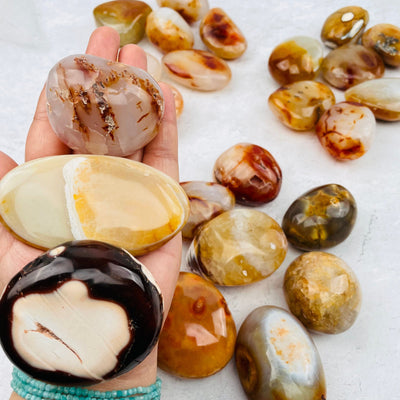 Carnelian Agate Tumbled Palm Stones in hand for size reference 