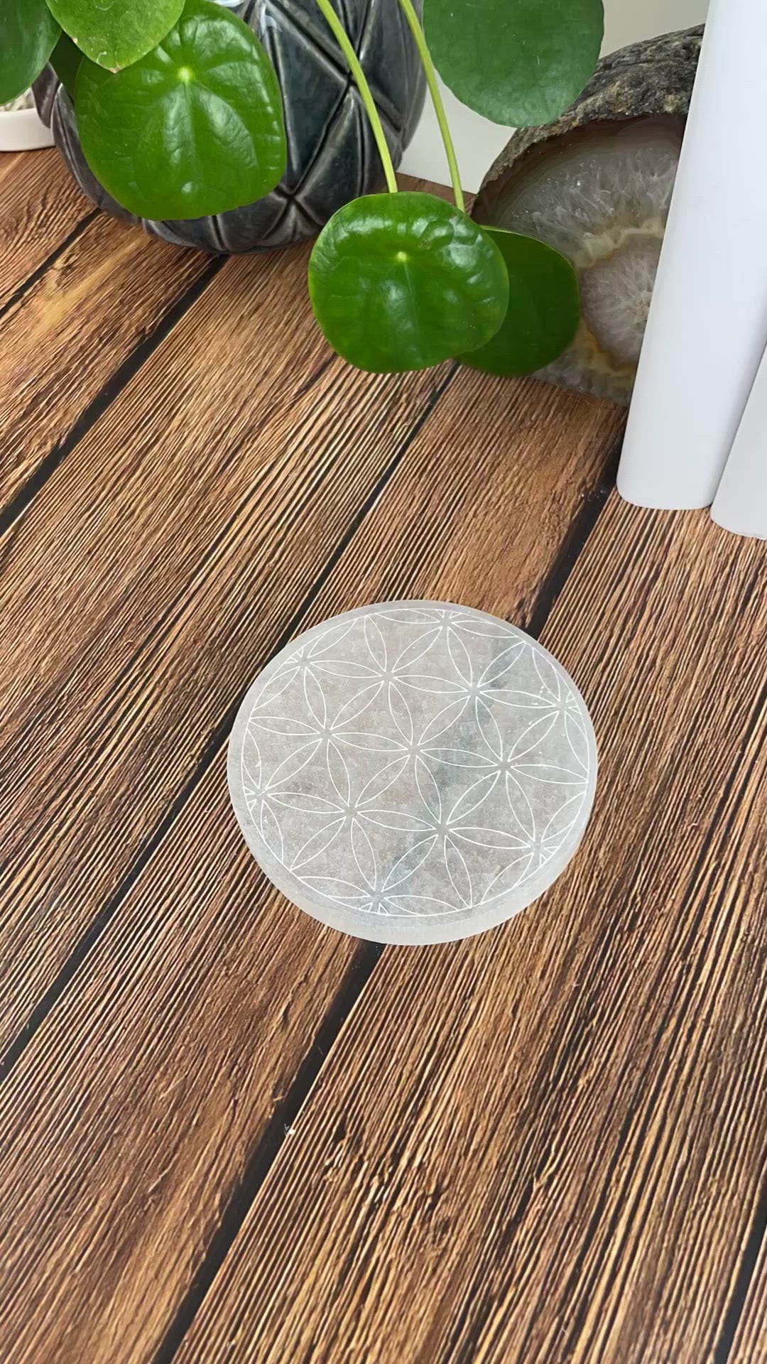 video of selenite round plate engraved with flower of life with charging stones being placed on engraving