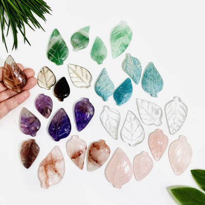A bunch of Gemstone Leaves in all the stones available, showing variation in markings and shades available and one in a hand for size reference