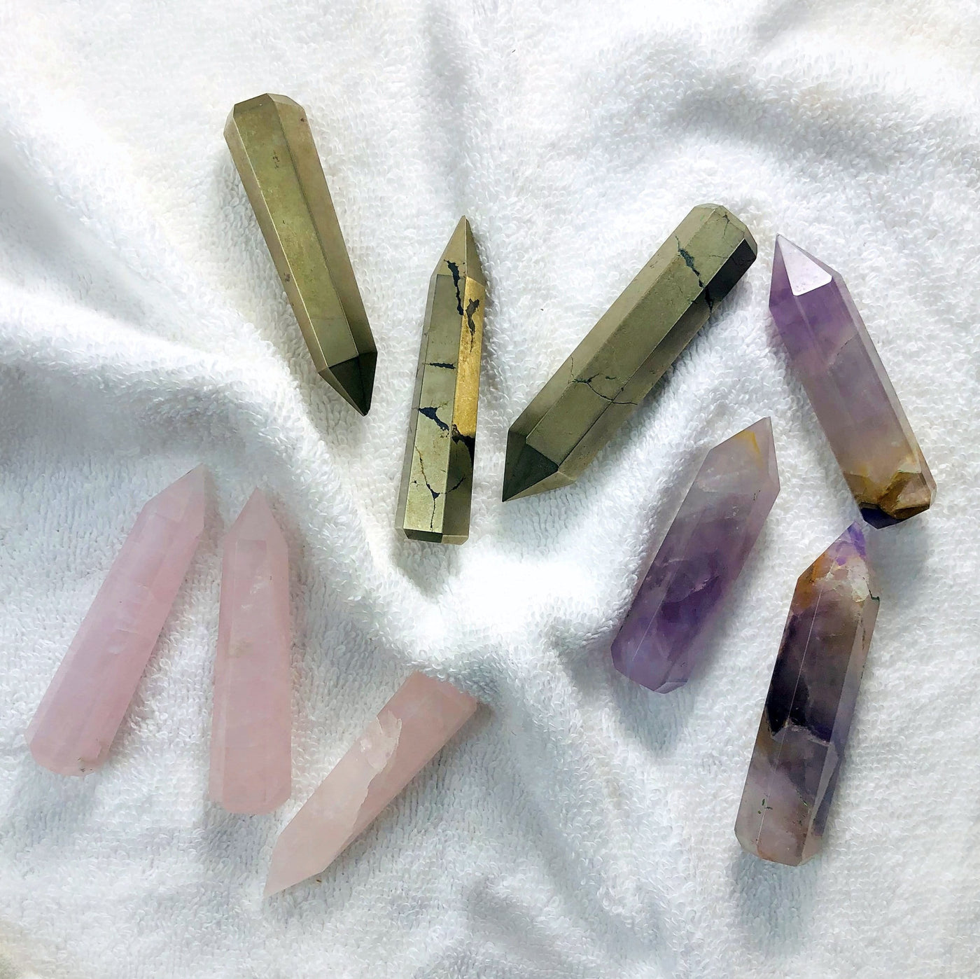 3 different colored Gemstone Pencil Polished Points displayed on white terry cloth