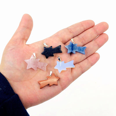 five shooting star stone pendants in hand for size reference