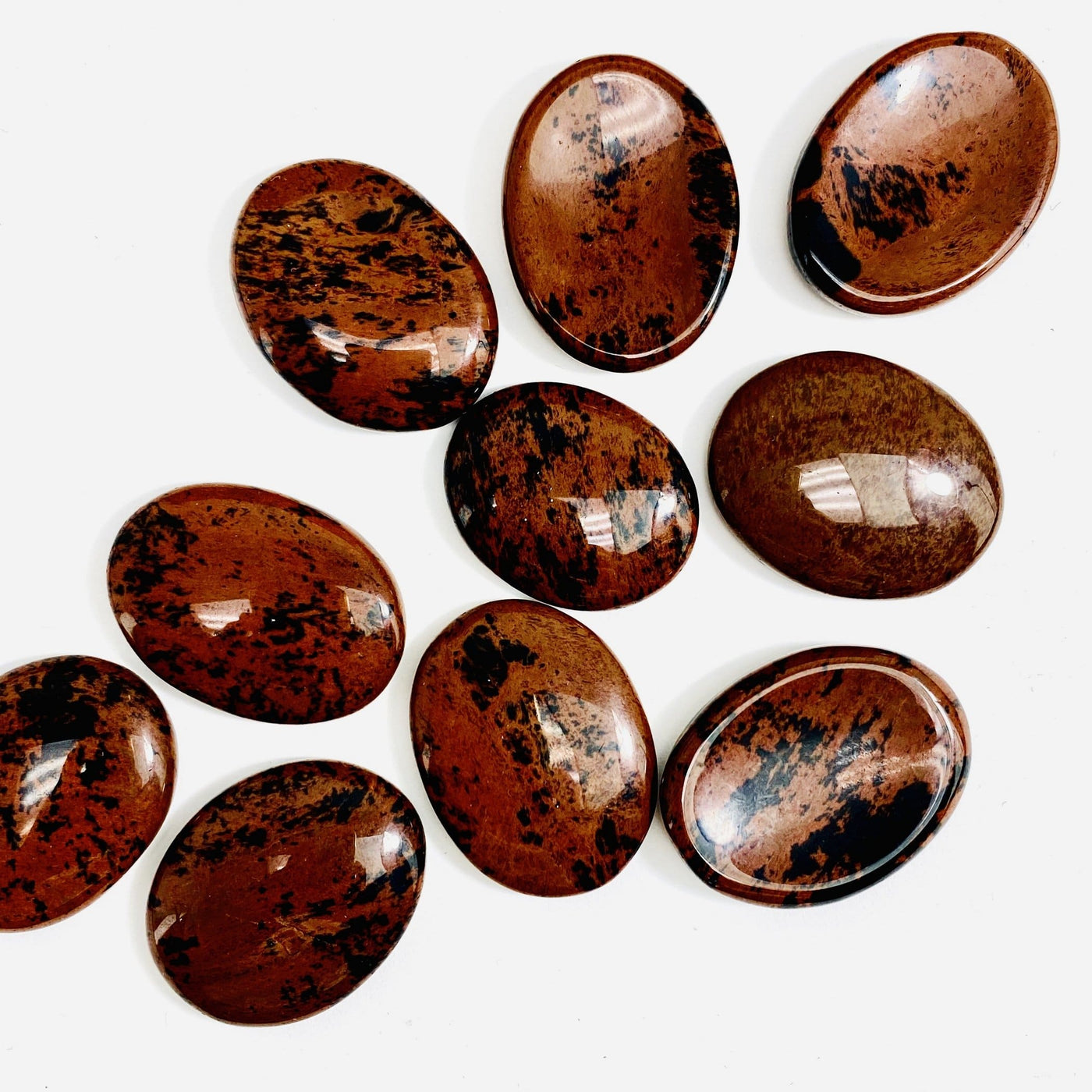 multiple thumb stones made of mahogany displayed to show the differences in the color shades 