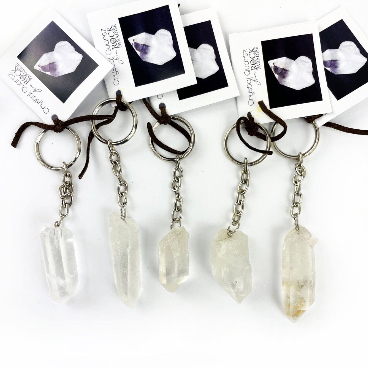 5 Crystal Quartz Keychains with tags on a table showing size and shape variations of this stock.