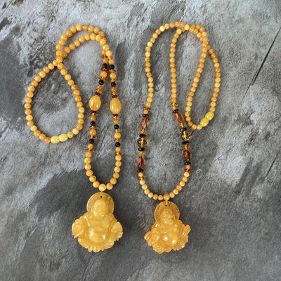 Amber Beaded Necklaces with Carved Buddha Pendants side by side