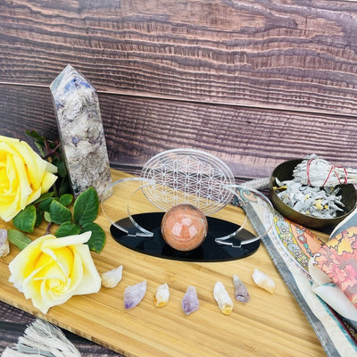 Acrylic Sphere Holder Crescent Moons with Flower of Life holding a sphere in an alter that consists of flowers and crystals.
