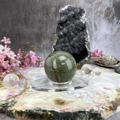 Acrylic Sphere Holder - Clear Oval Holder in an alter holding a sphere decorated with crystals and flowers.