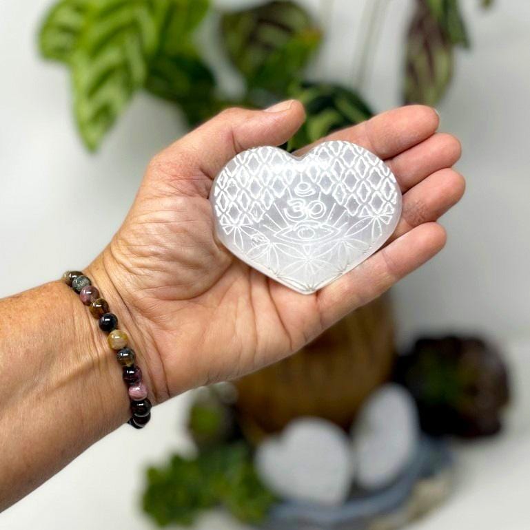 one selenite stone heart with eye engraving in hand for size reference and details
