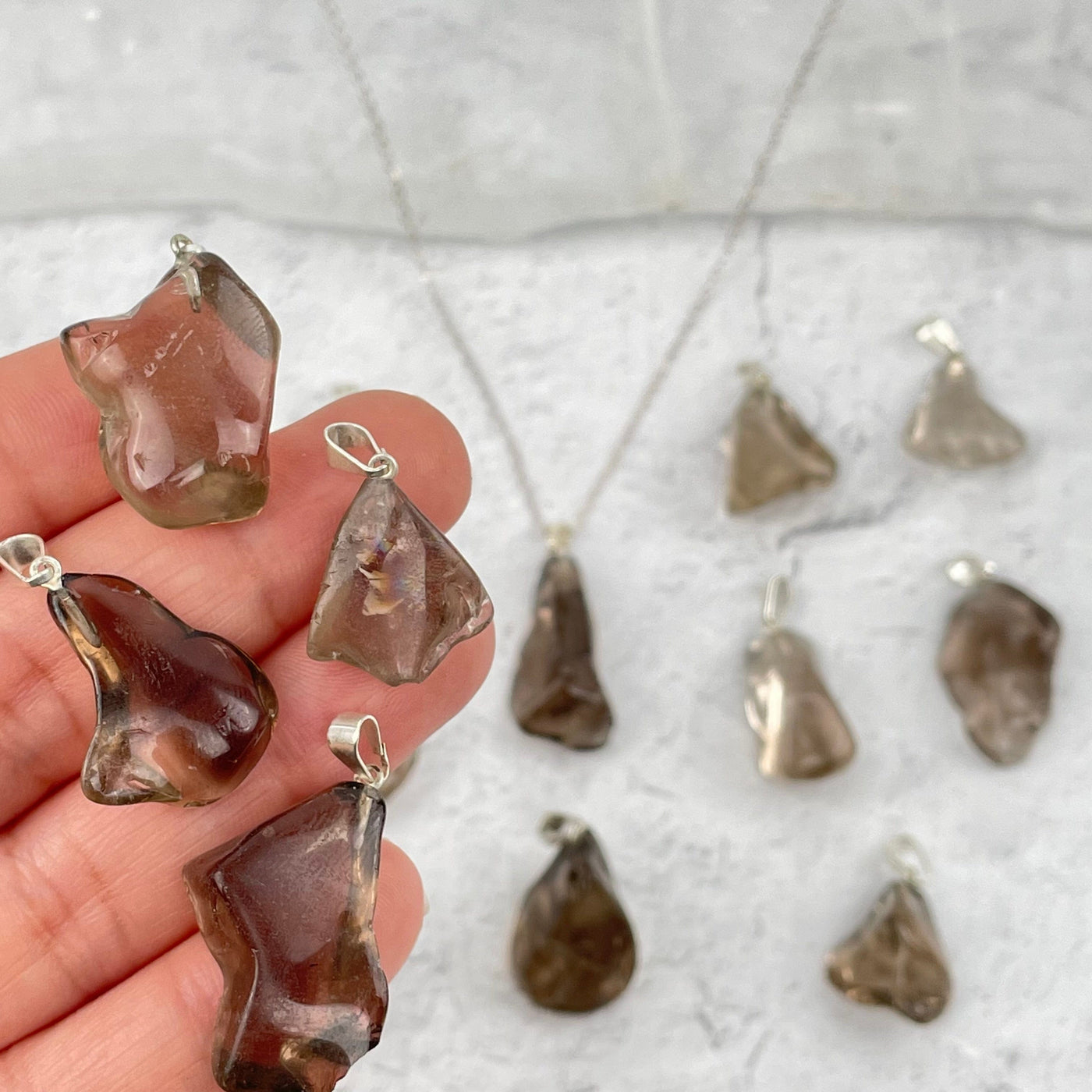 multiple smokey quartz pendants in hand for size reference 