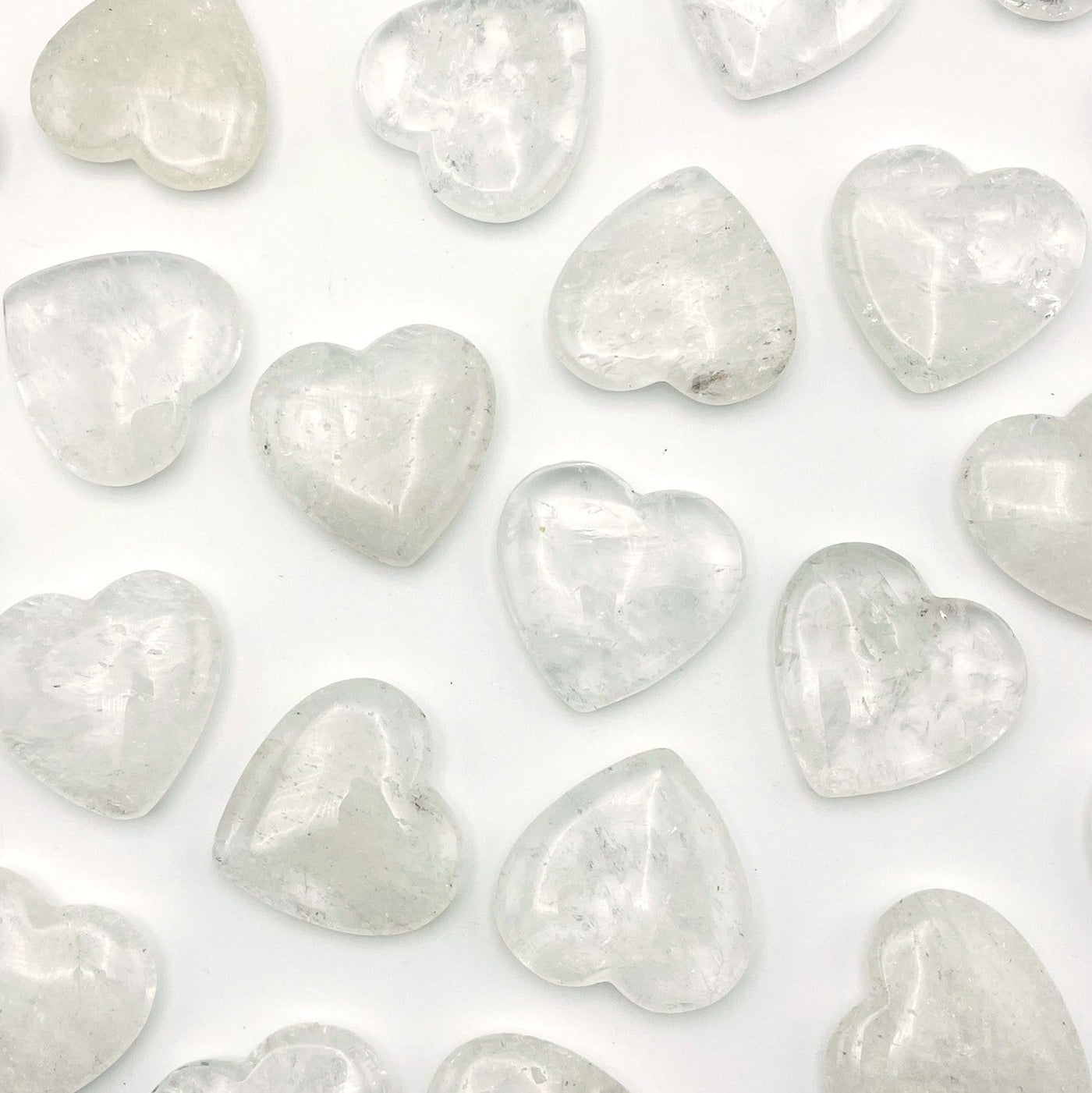 multiple crystal quartz heart shaped stones displayed to show the differences in the color shades 