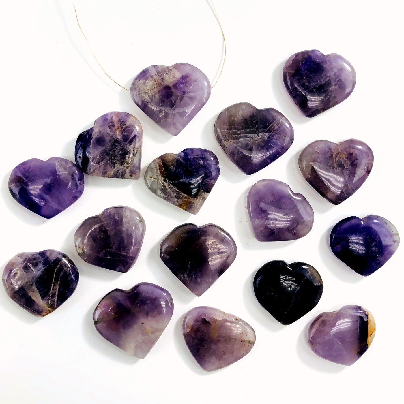 multiple amethyst head drilled heart shaped gemstones in a row one with a wire shown as a neckless