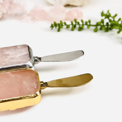 2 Rose Quartz Butter Spreaders with crystals and plants in the background