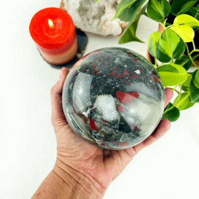 African Bloodstone Polished Sphere in a hand for size reference