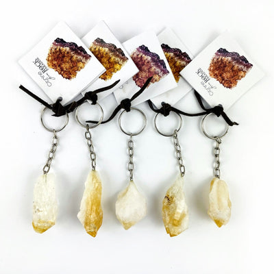 5 Citrine Point Keychains with tags on a table showing size and shape variations of this stock.