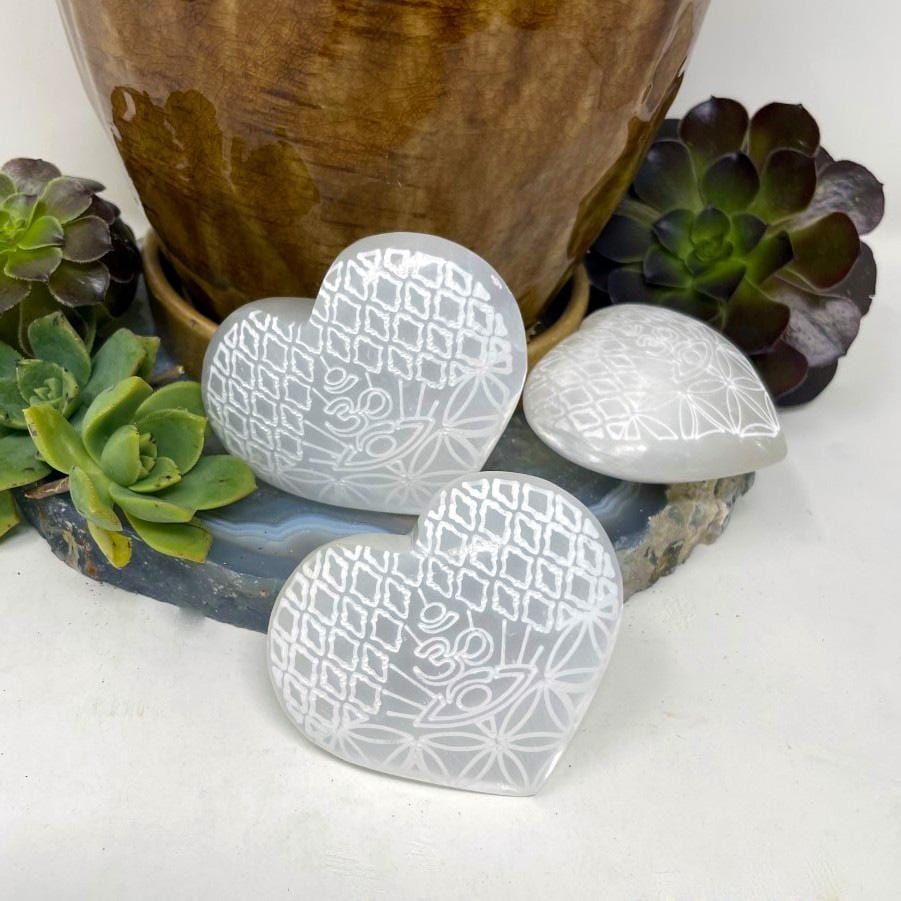 three selenite stone hearts with eye engraving on display