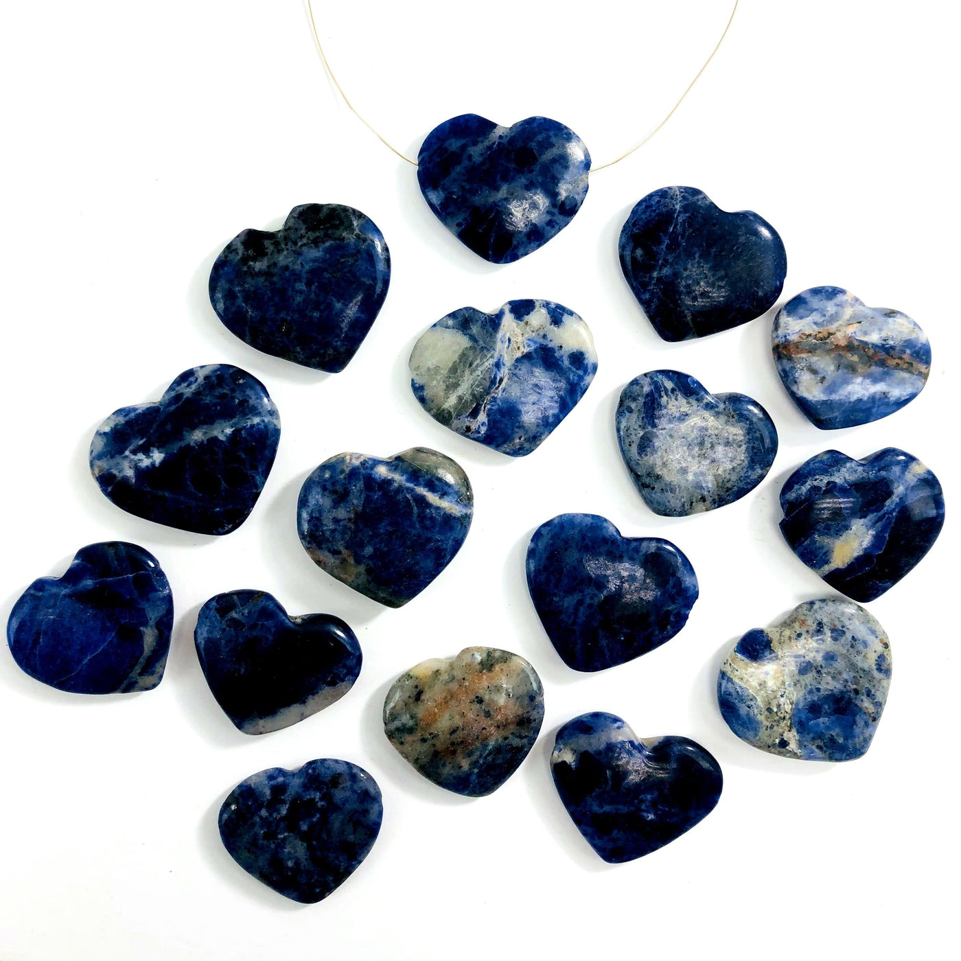 multiple sodalite head drilled heart shaped gemstones in a row one with a wire shown as a neckless