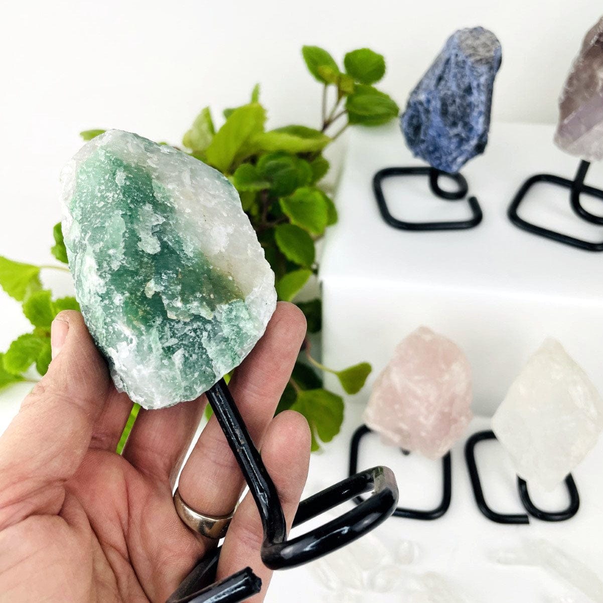 green quartz Rough Stone on Metal Stand up close in a hand