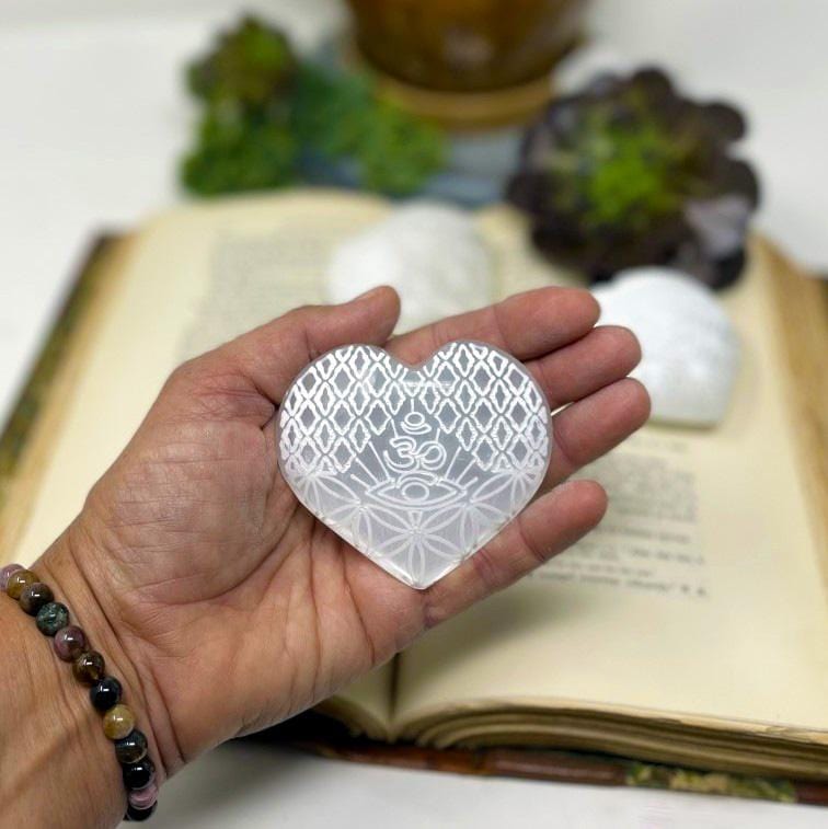 one selenite stone heart with eye engraving in hand for size reference