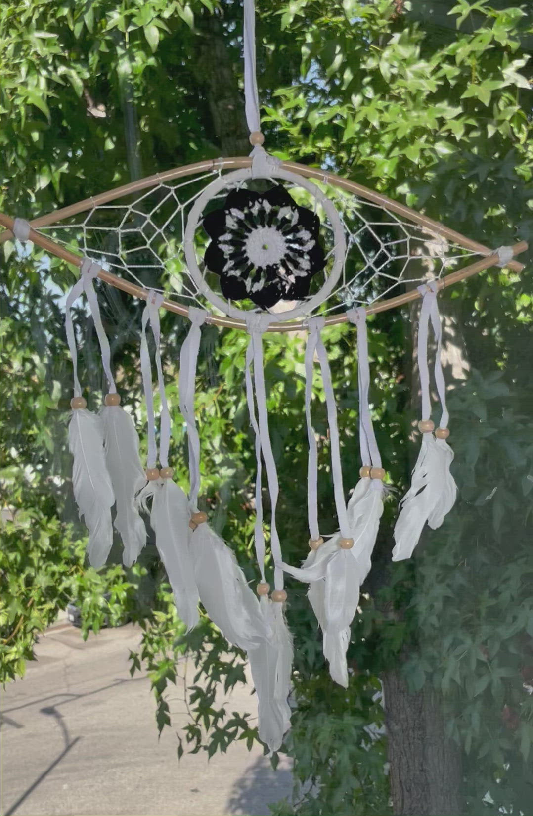 video of black eye dream catcher with a tree in the background as the wind blows through