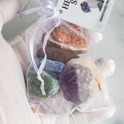 Healing Stone Set - 7 Rough Chakra Stones, Tied & Tagged in a hand up close