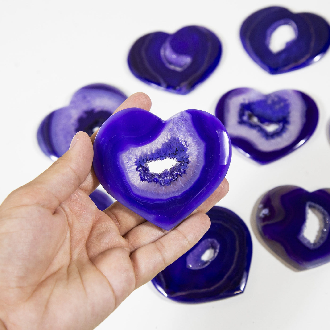 hand holding up purple agate heart with others in the background