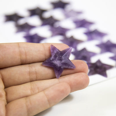 hand holding up amethyst star cabochon with others blurred in the background