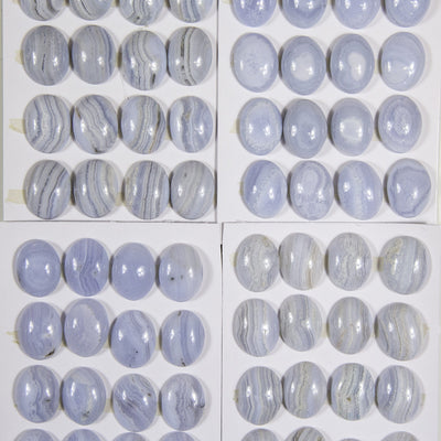 multiple Blue Lace Agate Oval Cabochons displayed on several sheets to show various natural formation patterns and hues of blue brown grey and white