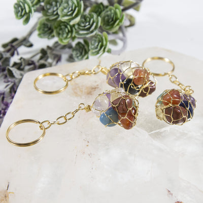 angled view of seven stone chakra tumbled stone gold keychains for thickness