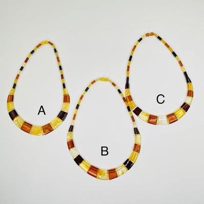 Aerial view of necklace options a, b, c displayed on a white surface.