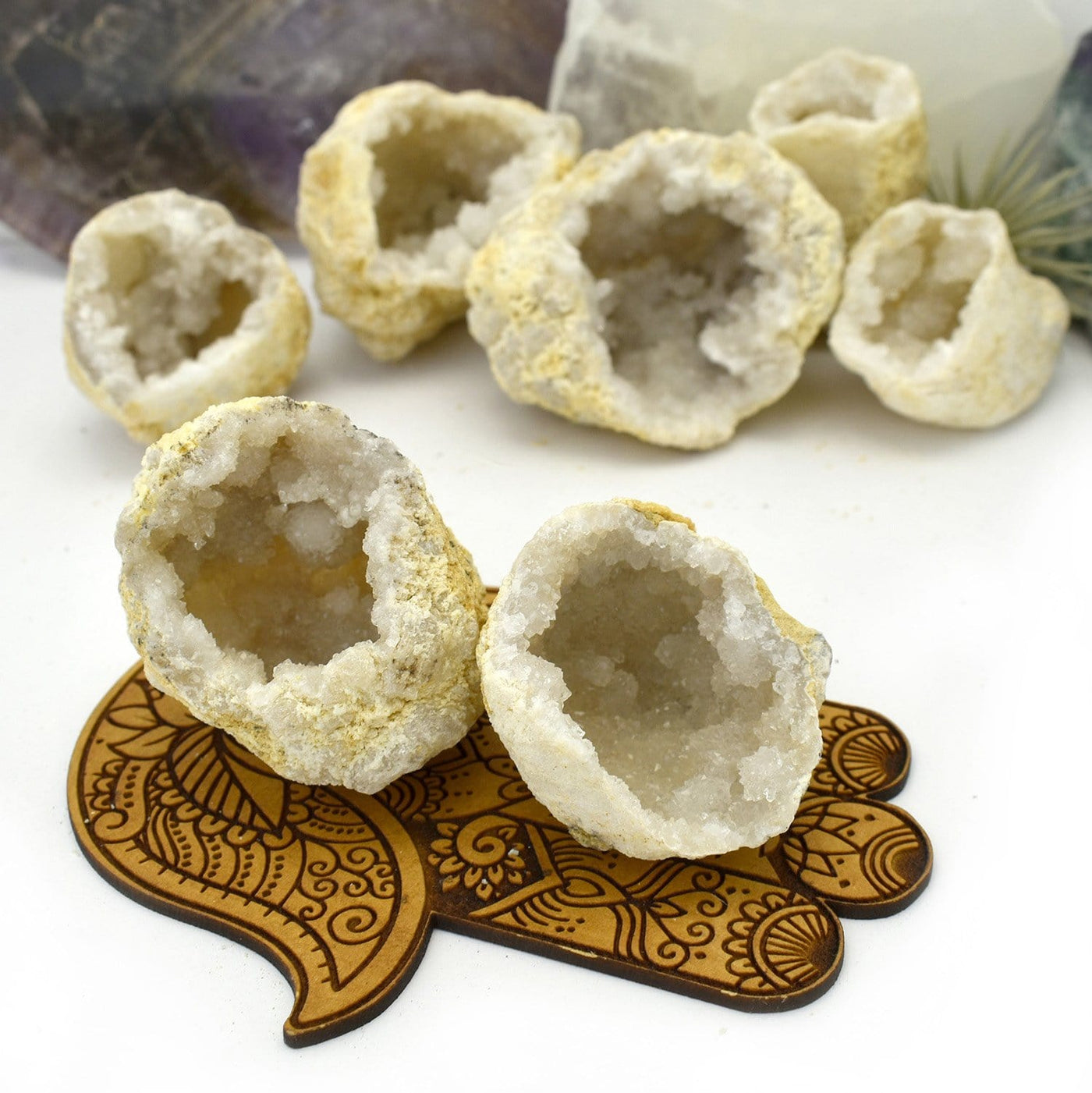 2 White Druzy Geodes on a wooden hamsa hand with others in the background