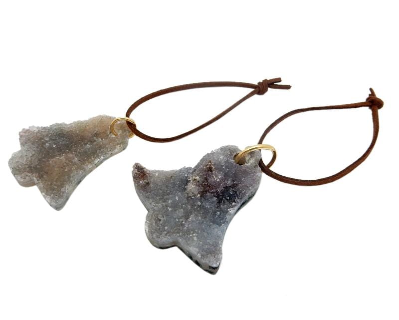 druzy quartz cut into a bell shape and strung on a brown cord to make an ornament.