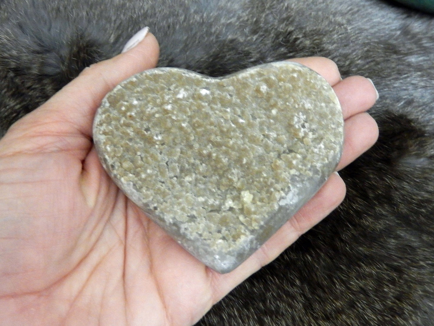 hand holding up druzy heart on fur background