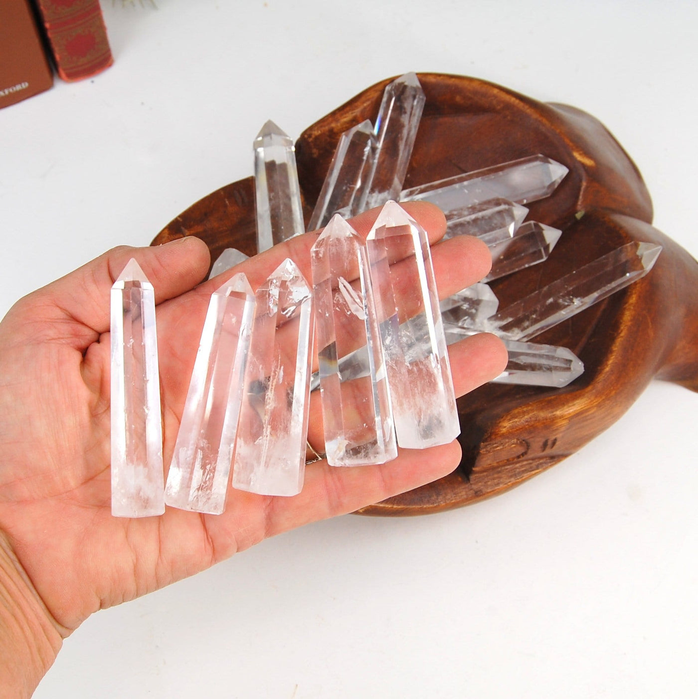 hand holding up 5 Crystal Quartz Obelisks with others in the background