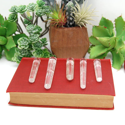 5 Double Terminated Crystal Quartz Points Different Size on Red Book Background.