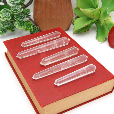 Side Angle 5 Double Terminated Crystal Quartz Points Different Size on Red Book Background.