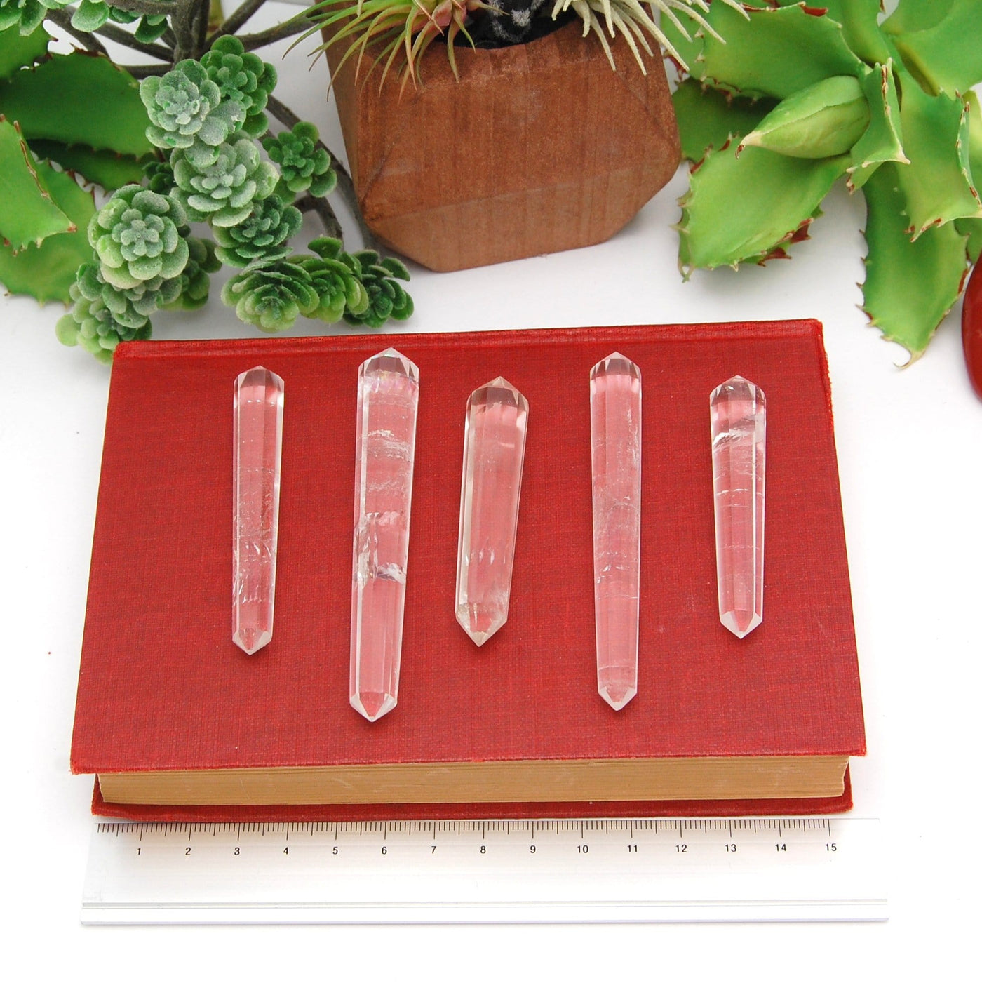 5 Double Terminated Crystal Quartz Points Different Size on Red Book Background.