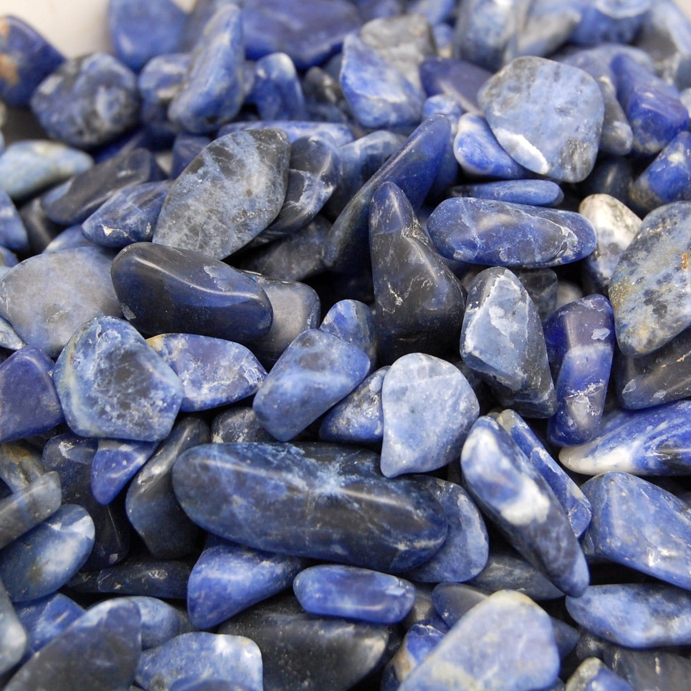 close up of tumbled sodalite small stones showing hues of blue, black and some white 