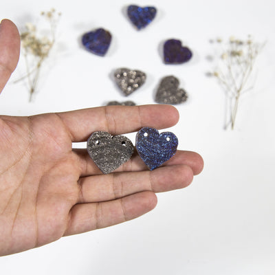 hand holding up Chalcedony Heart Titanium Coated Blue or Platinium Double Drilled beads with others blurred in the background