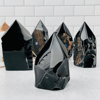 Multiple Black Obsidian Semi Polished Points displayed to show the differences in the sizes 