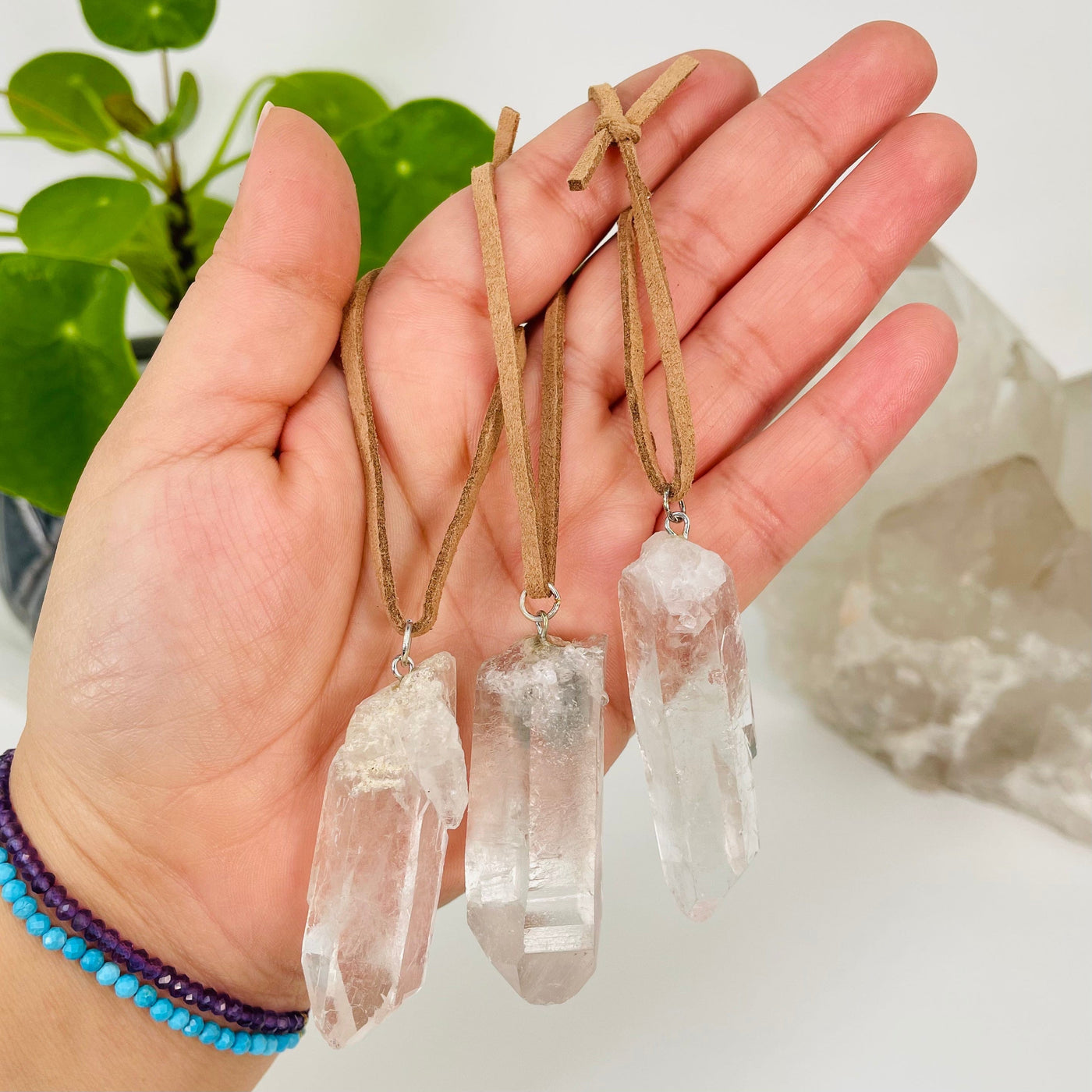 multiple crystal quartz point ornaments in hand for size reference 