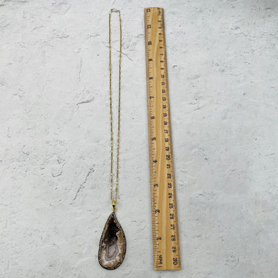 necklace next to a ruler for size reference 
