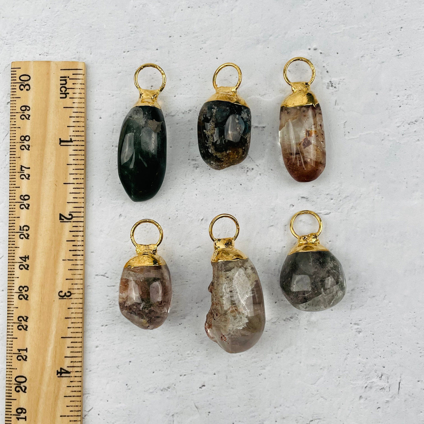 pendants next to a ruler for size reference 