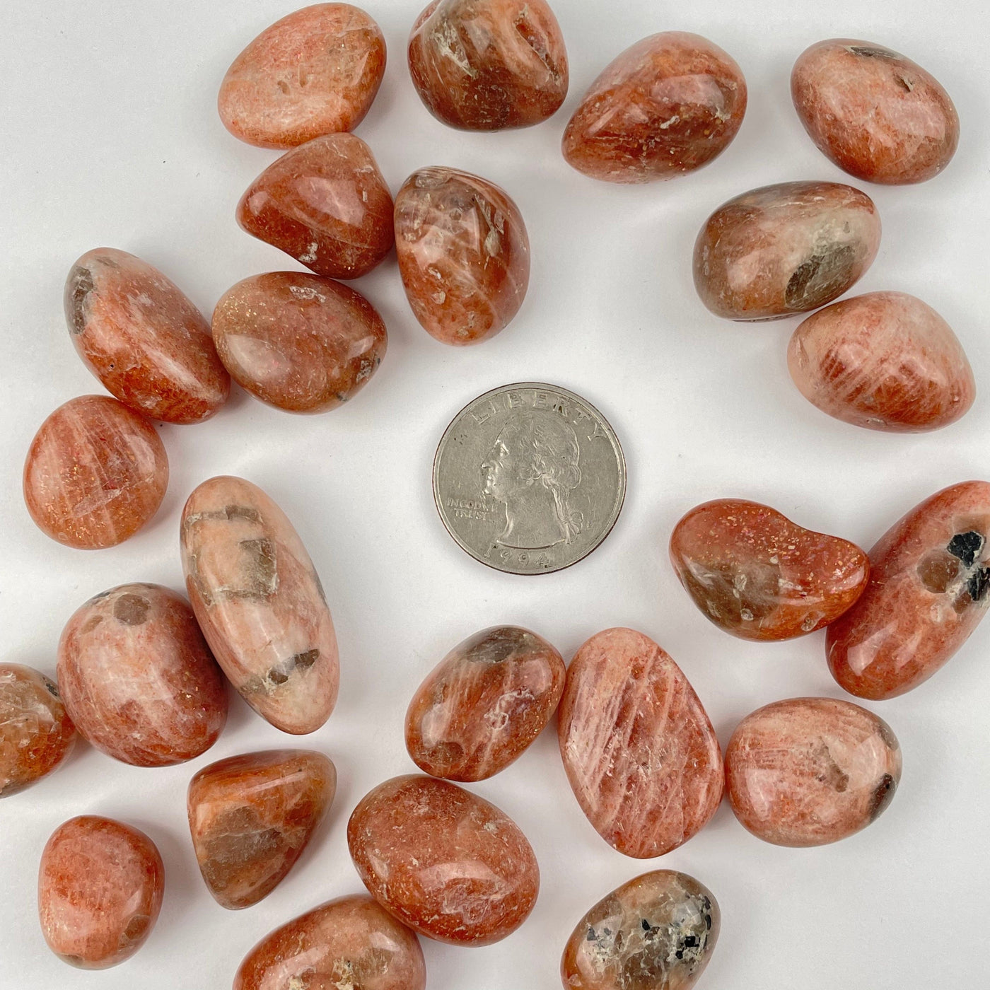 Golden Sunstone Tumbled stones next to a quarter for size reference 