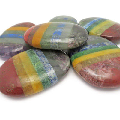 angled view of many large seven chakra palm stones in a pile for thickness