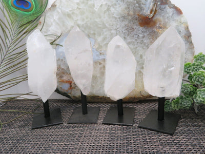 multiple crystal quartz points on metal stand displayed to show the differences in the shapes 
